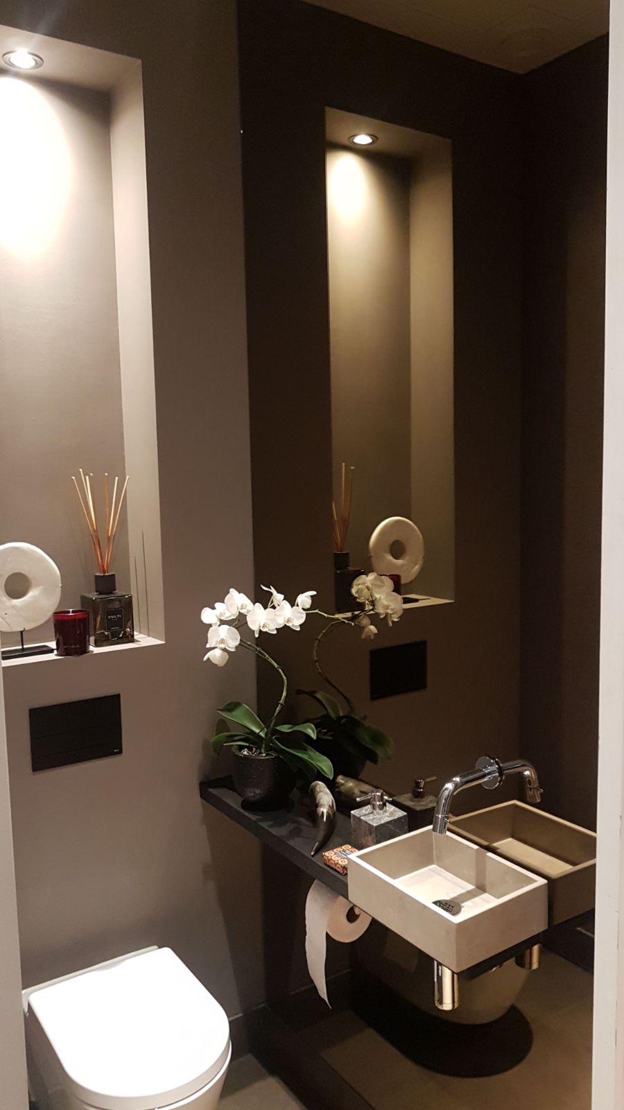 Bronzen spiegel over hele muur van het toilet